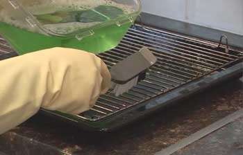 Image of a hand cleaning a grill.